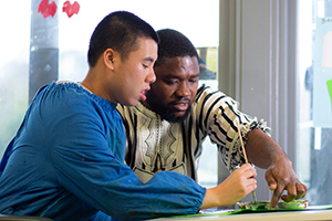 Support worker at Able Australia assisting a client with a painting activity, fostering creativity and connection through art.