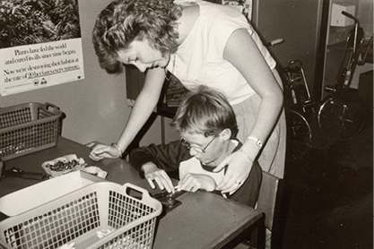 Black and White photo woman with young child reading braille