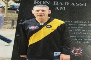 Able client Colin standing in front of a Ron Barassi statue wearing a Richmond Tigers jersey