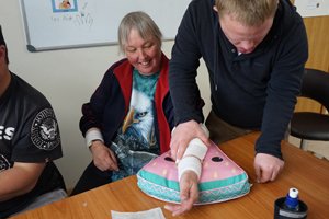 Two Able clients practising First Aid with one wrapping a bandage around the other's arm.