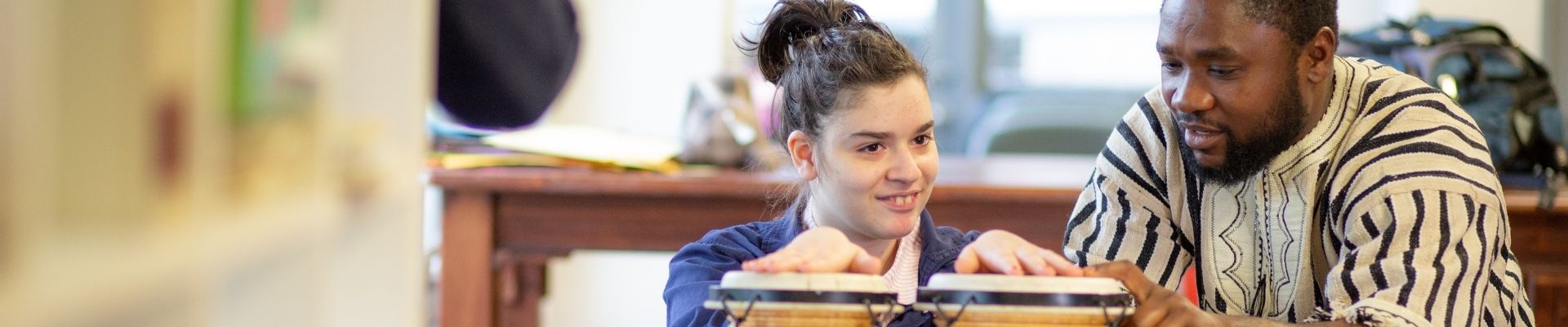 Able Australia Day Programs - image of a female with her hands on drums being supported by her Support Worker